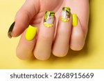 Female hands with black and yellow nail design. Yellow nail polish manicured hands. Female hands on yellow background