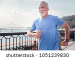 Small photo of Sport with me. Confident senior unshaken man spending time on fresh air holding dumbbells and running.