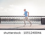 Small photo of Free of movements. Aged athletic unshaken man being on the quay doing cardio exercises and running.