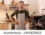 Cheerful barista. Cheerful dark-haired bearded barista smiling while welcoming guests
