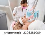 Small photo of Female in a protective mask performs laser skin resurfacing procedure