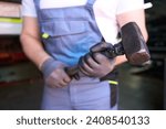 Small photo of Vehicle mechanic with sledgehammer in automotive repair shop