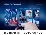 VOD service screen with remote control in hand. Video On Demand television internet stream multimedia concept
