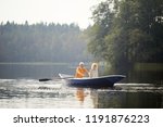 Happy senior couple in casual clothing sitting on boat and enjoying romantic date on lake, elderly man rowing oars