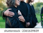 Small photo of Hand of mature man on shoulder of his wife or sister with handkerchief lamenting passes away relative or family member during funeral service