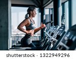 Side view of beautiful muscular woman running on treadmill.