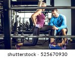 Young attractive blonde female doing lunge exercise in modern fitness center with assistance of her personal trainer.