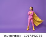 Little child is playing superhero. Kid on the background of bright ultra violet wall. Girl power concept. Yellow, pink and  purple colors.