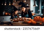Small photo of Mother and her daughter having fun at home. Happy Family preparing for Halloween. Mum and child cooking festive fare in the kitchen.