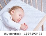 Small photo of The baby sleeps safely and sweetly in his wooden crib on a terry sheet with an elastic band. Infant sleeping in bedside bassinet. Safe co-sleeping in bed side cot. Little girl taking a nap. Copy space