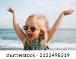 Funny kid girl playing outdoor surprised emotional child in sunglasses 3 years old baby raised hands family vacations 