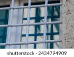 Small photo of window with grate, building with old windows and white grates. new and modern glass on an ancient building. window closed by sturdy ancient wrought iron grates
