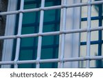 Small photo of window with grate, building with old windows and white grates. new and modern glass on an ancient building. window closed by sturdy ancient wrought iron grates