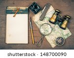 Small photo of Old notebook, compass, map, vintage binoculars, pen and inkwell, pocket knife, magnifying glass on wooden background