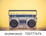 Retro outdated portable stereo boombox radio cassette recorder from 80s front yellow background. Vintage instagram old style filtered photo