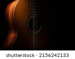 Classical guitar close up, dramatically lit on a black background with copy space