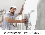 Hands man plasterer construction worker at work with trowel, plastering a wall, closeup
