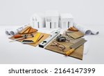 Small photo of samples of wooden flooring, samplers of laminates, tiles and baseboards with carpenter tools on blueprint with model house, interior design, finishing materials shop, planning, sale and installation