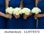 four bridesmaids in blue dresses holding white rose bouquets