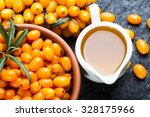 Small photo of Sea buckthorns oil and fresh ripe berries close up on black stone background