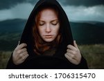 ginger woman in black hood stands in the rain. Dramatic and fantastic shooting, fashionable toning, creative computer colors