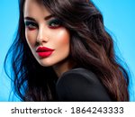 Portrait of beautiful young woman with bright blue makeup. Beautiful brunette with bright red lipstick on her lips. Pretty girl with long black hair. Closeup face of brunette woman. 