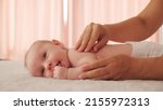 Small photo of Mother doing massage on her healthy infant baby. Small caucasian newborn laying on his belly while his mother is performing a massage for his small back and developing muscles.