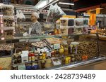 Small photo of Barcelona, Spain – April 17, 2018: Horizontal view of a nuts, dried fruits and cooking herbs stall with its elderly owner in the old Abaceria Central Market of the Gracia neighborhood