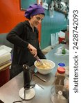 Small photo of Barcelona, Spain – April 17, 2018: Vertical shot of a cook preparing filling for the pasta in her stall of the old Abaceria Central Market in the Gracia neighborhood