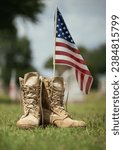 Small photo of Old military combat boots against American flag in the background. Memorial Day or Veterans Day, sacrifice concept.