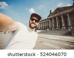Happy bearded guy taking selfie near Reichstag in Berlin. Funny hipster student taking picture for travel blog in Germany.
