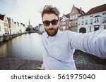Funny bearded hipster taking selfie portrait in Bruges old town, Belgium. Handsome male blogger takes photo for social media.
