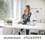 Businesswoman telephoning using cellphone while working at ergonomic standing desk.