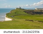 South Downs countryside, Beachy Head, Eastbourne, East Sussex, England. White chalk cliffs and Belle Tout lighthouse now residence, building moved back from eroding cliff edge. Unrecognisable people.