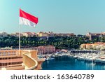 National flag of of the Principality of Monaco and view of port