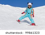 Portrait of cute little girl skiing downhill on a sunny day. Skier wearing a protective crash helmet and ski goggles. Copy space for text