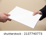 Small photo of Businessman handing over a paper document to a fellow employee or customer. Concept on the topics: exchange of information, conclusion of a contract, transfer of documents.