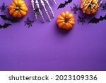 Halloween flat lay composition with pumpkins, bony hands, spiders, bats on purple background. Happy halloween banner mockup.
