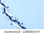 Blue and white ribbons with confetti on blue table. Israel Independence Day, Yom Haatzmaut greeting card design, banner template.