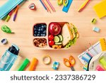 School lunch box with healthy food and school supplies on wooden table. Back to school concept. Top view. Flat lay.
