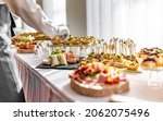 Small photo of woman hands of a waiter prepare food for a buffet table in a restaurant