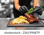 woman chef hand decorated Pork ribs with french fries and cheese sauce on kitchen