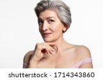 Small photo of Pretty old lady with beautiful face posing for camera on white copy space. Charming, attractive senior woman touching chin with hand studio portrait. Oldster and day facial skin care, spa and hygiene