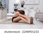 Small photo of Inflexible woman improving flexibility by working out at home