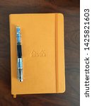 Small photo of San Diego, CA - March 2, 2018: Rhodia notebook in orange color and a blue TWSBI 580 fountain pen on top. Top down view of both on a desk.