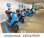Small photo of San Francisco, CA - July 28, 2023: Blue electric mopeds by Revel, charging inside a parking garage. Popular rental scooter company in SF.