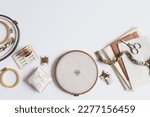 cross stitch embroidery accessories. Linen cloth in hoop on white background with floss, scissors and cloth. Indoor hobby concept.