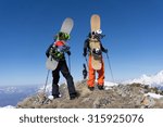 Snowboarders standing on top of a snowy mountain
