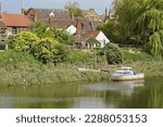 Small photo of riverside houses with a motorboat moored on the river Witham in springtime