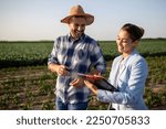 Pretty business woman and handsome farmer signing documents on field in summer time